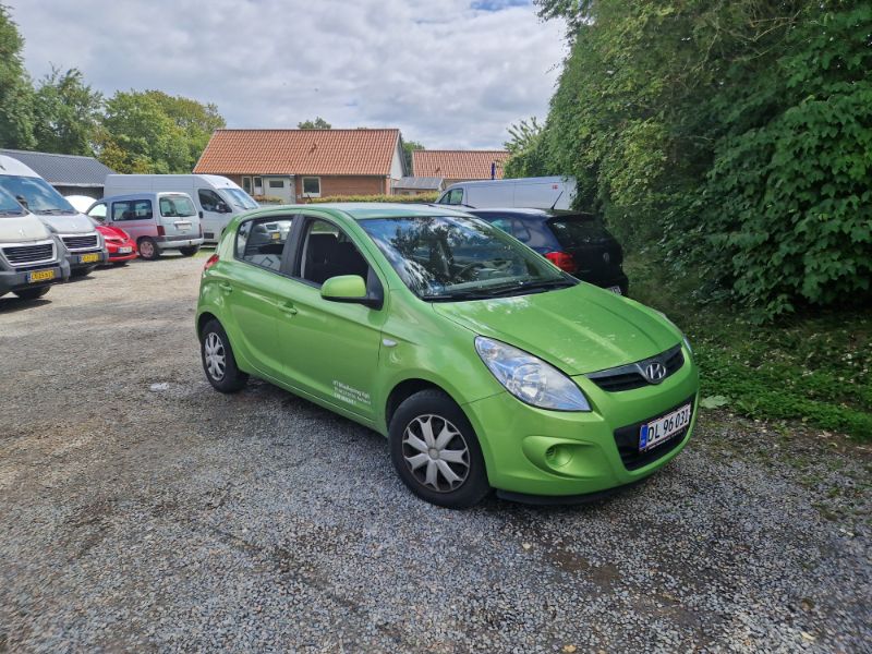 En grøn bil af mærket Hyundai parkeret på en parkeringsplads.